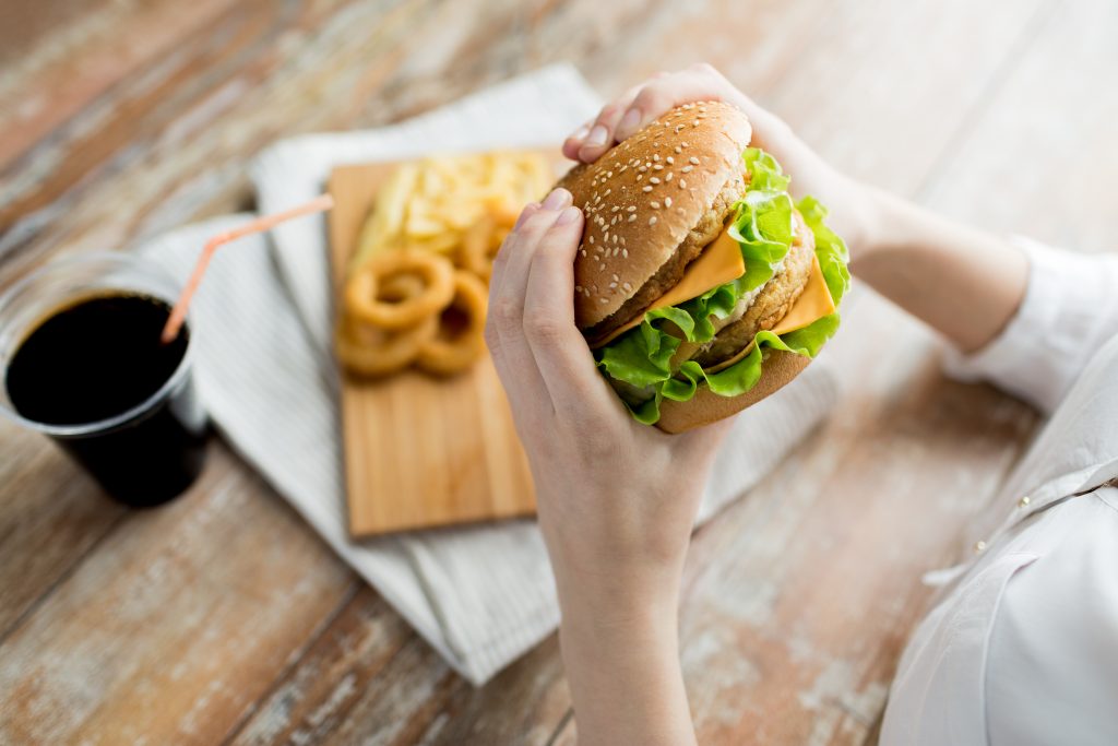 Dieta do biura – kobieta jedząca fast food w pracy 